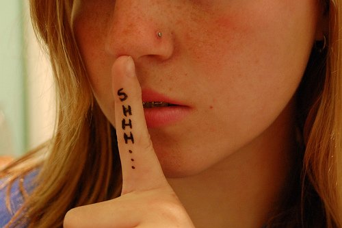 Girl with finger to mouth saying shhhh